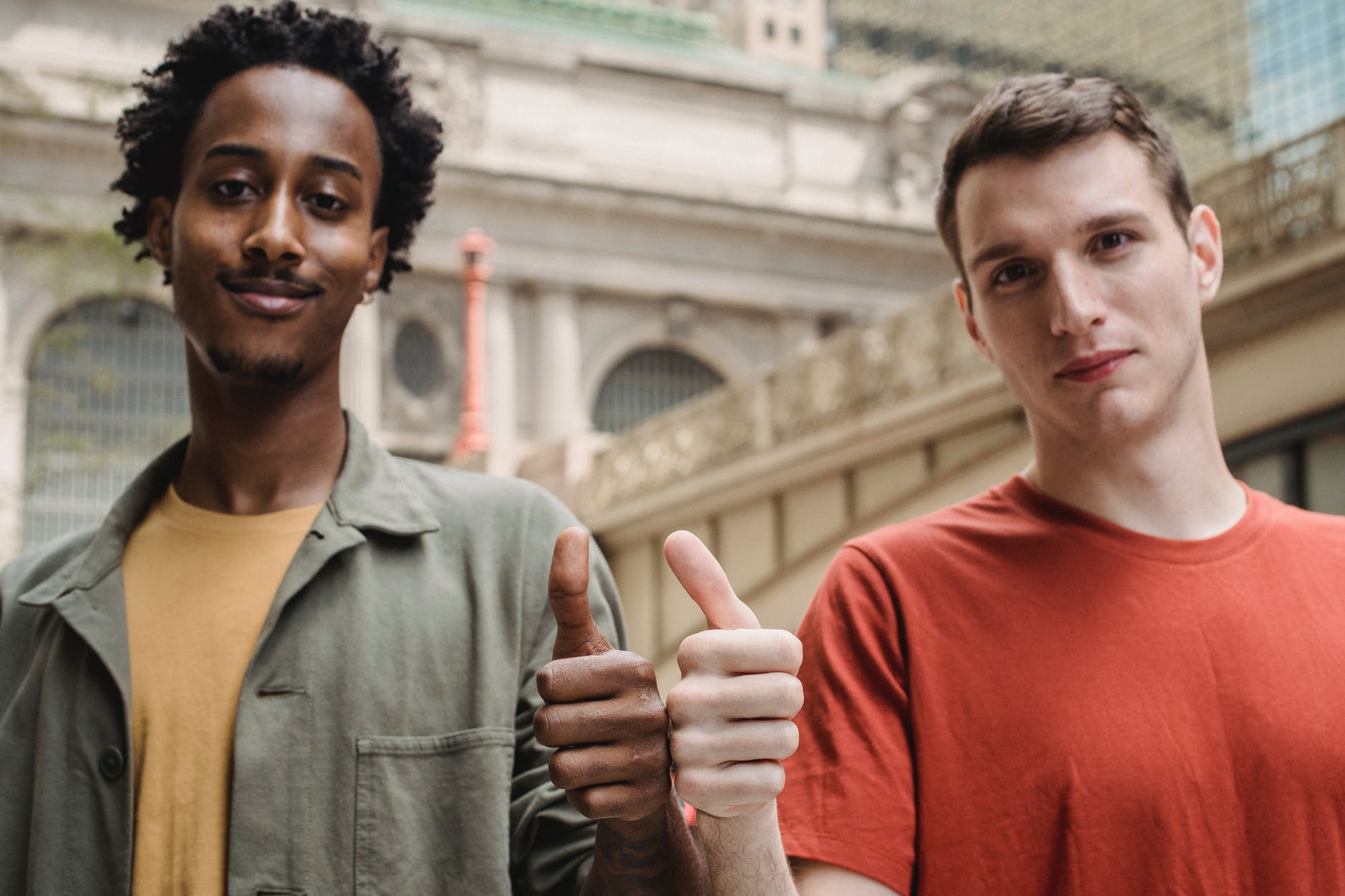 positive young multiracial guys demonstrating thumbs up sign at camera